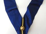 a close up of a blue scarf with a gold medal on it