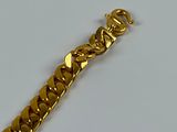 a gold bracelet with a chain on it on a white surface