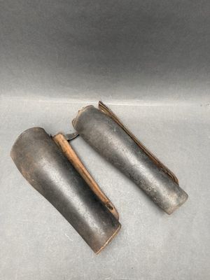 pair of old metal pipe holders in a box on a white surface