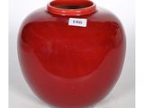 un vase rouge muni d'une étiquette, posé sur une table