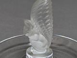 a glass bird on a glass plate on a table