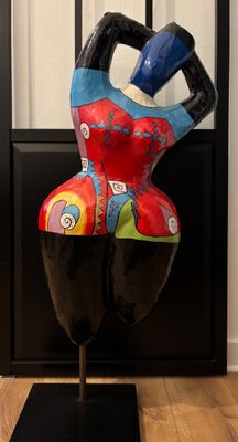 une sculpture colorée représentant une femme, posée sur un socle noir