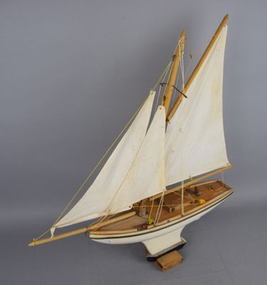 wooden model of a sailboat with white sails on a wooden stand