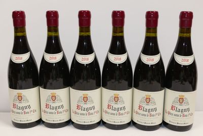 six bouteilles de vin rouge sont alignées sur une surface blanche