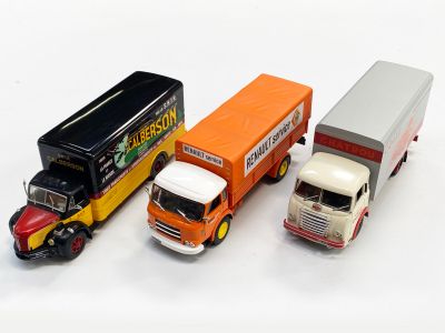 trois camions miniatures placés les uns à côté des autres sur une surface blanche