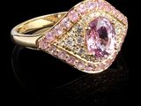une bague sertie d'un saphir rose et de diamants, posée sur un fond noir