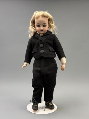 une image représentant une poupée représentant une petite fille en tailleur noir
