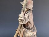 statue of a man holding a rifle on a wooden base