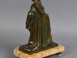 bronze statue of a man with a hat and cloak on a marble base