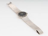 a close up of a watch on a white surface with a silver band