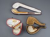 three different types of smoking pipes in a case on a table