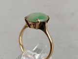 an image of a gold ring with a green stone in it