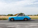 blue porsche parked on the side of the road in front of a field