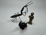 une statue représentant un homme et un insecte sur une surface blanche
