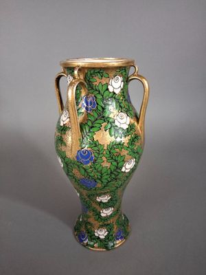a green vase with blue flowers on it sitting on a table
