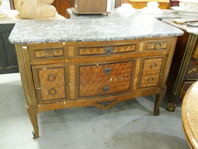 une commode au plateau en marbre placée au milieu d'une pièce