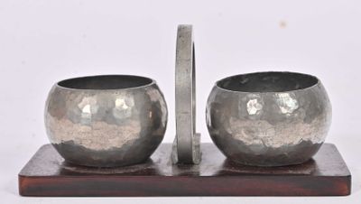 deux bols en argent posés sur un socle en bois, sur fond blanc