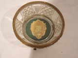 a glass bowl with a gold medallion in it