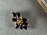 a gold pen and a blue flower brooch on a table