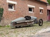an old car that is parked in front of a brick building
