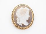 Une broche en or représente le profil d'une femme.