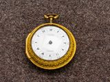 une montre de poche en or avec un cadran blanc sur un fond marron