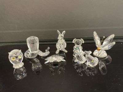 quatre figurines en verre représentant des oiseaux et des fleurs, posées sur une table