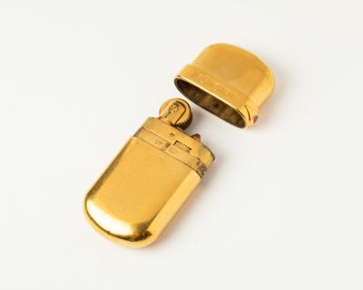 an image of a gold lighter sitting on top of a white surface