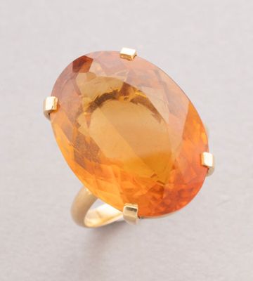 a close up of a ring with an orange stone on it