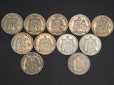 six different types of silver coins on a black surface