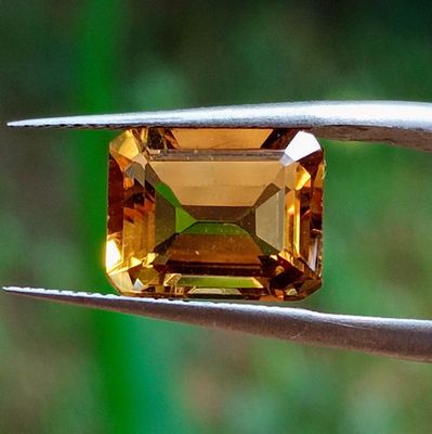 un gros plan d'un diamant jaune tenu par une paire de pinces