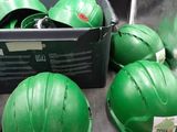 many green hard hats sitting on a metal tray