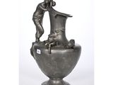 a silver vase that has a statue on top of it