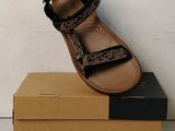 tan and black sandals on top of a cardboard box on a white surface