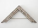 a close up of a silver broochle on a white background