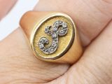 a gold signet with a diamond in it on a person ' s finger