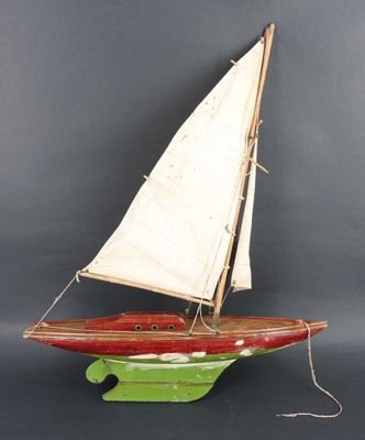 un petit voilier en bois muni d'une voile blanche