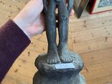 a person holding a statue of a man on a pedestal