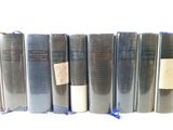 several books are lined up in a row on a white surface