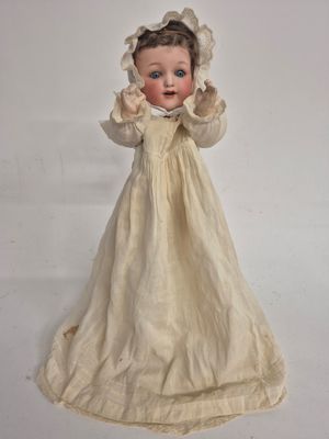une poupée qui porte une robe blanche et un bonnet