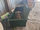 une boîte verte contenant un marteau, posée par terre