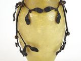 un vase jaune orné de feuilles noires, posé sur un socle