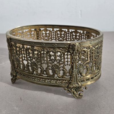 un panier ancien en laiton au motif ouvragé posé sur une table