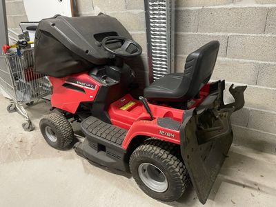 a red lawn mower parked in front of a building