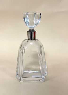 flacon de parfum en verre transparent muni d'un bouchon argenté, posé sur un fond blanc