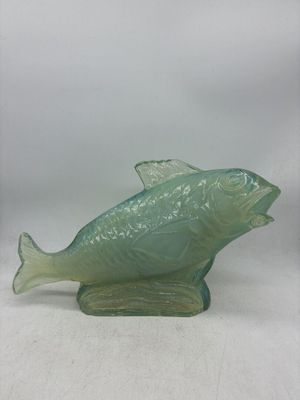 une figurine de poisson en verre posée sur une surface blanche