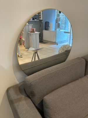 une photo d'un salon avec un canapé et un miroir rond