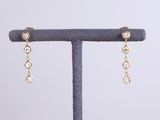 une paire de boucles d'oreilles en or et diamants, présentée sur un présentoir