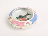 a small bowl with a fish in it on a white surface