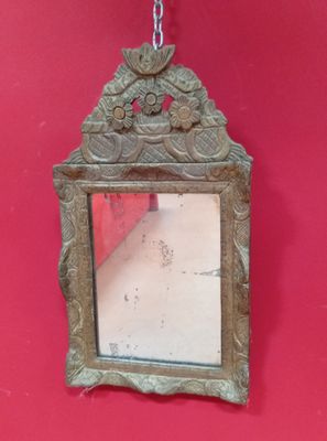 un miroir accroché à un mur rouge, entouré d'une chaîne